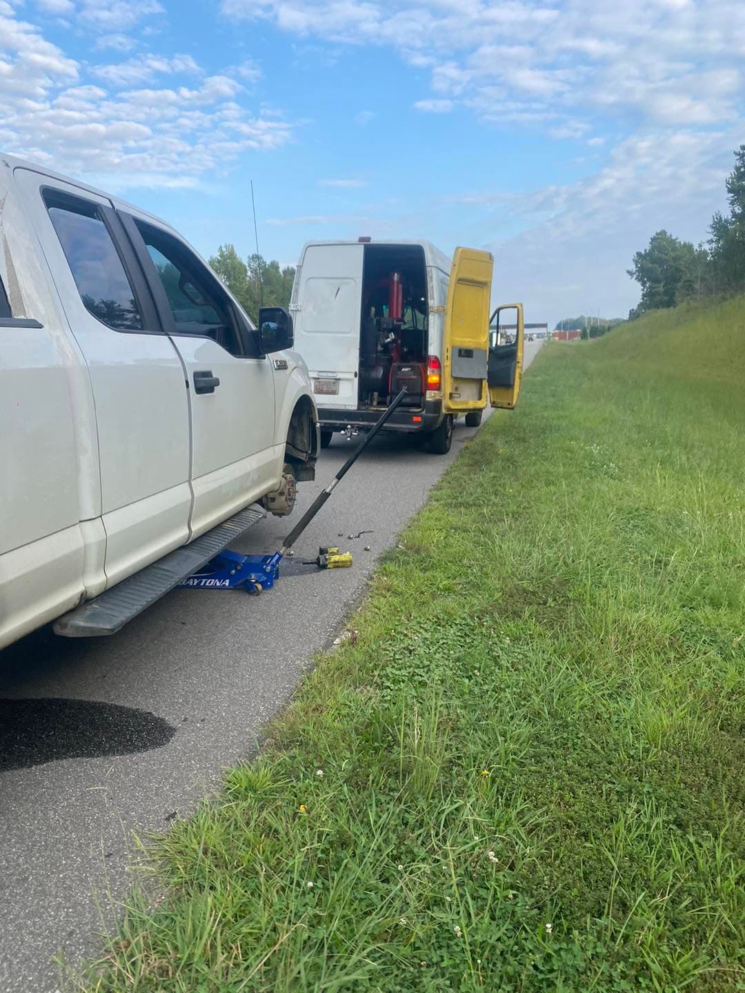 Tires 4 Less Roadside technician servicing a tire on the shoulder of a highway